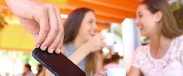 Distracted friends talking in a bar and close up of a thief hand stealing phone on foreground Rekord lavt antal tyverier i sommerferien